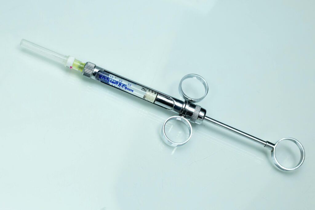 Detailed image of a stainless steel syringe with measurement markings on a white background.